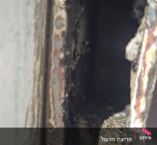 תקריב של חור שנוסר או נפרץ בדופן מתכת של כספת